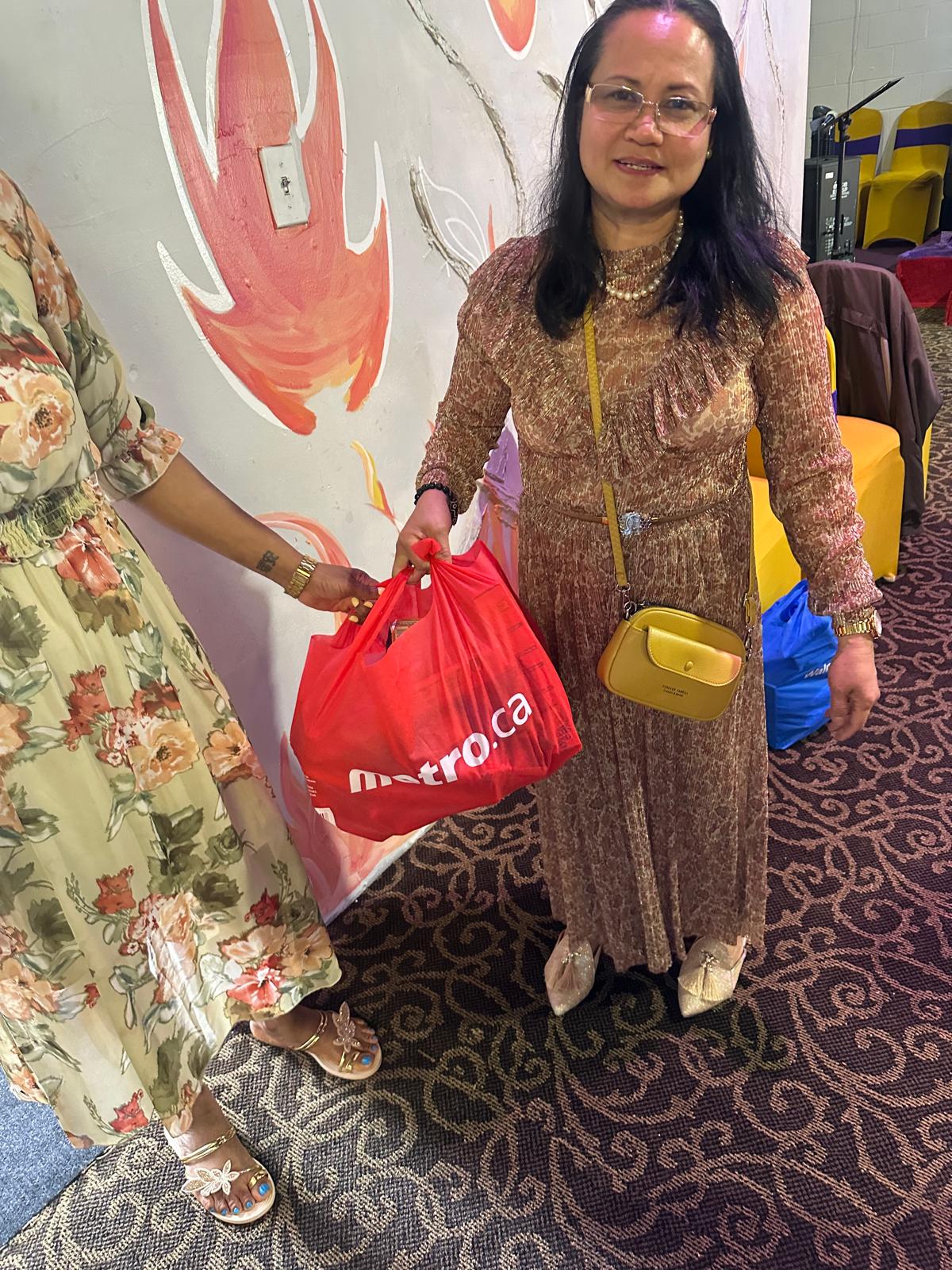 A volunteer handing a bag of groceries to a community member